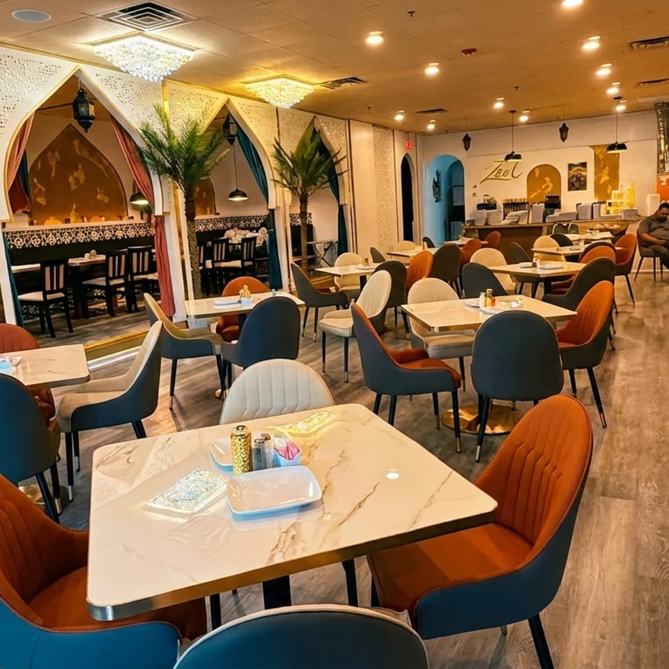 Spacious restaurant interior with modern tables, colorful chairs, booth seating, and decorative archways with palm trees.