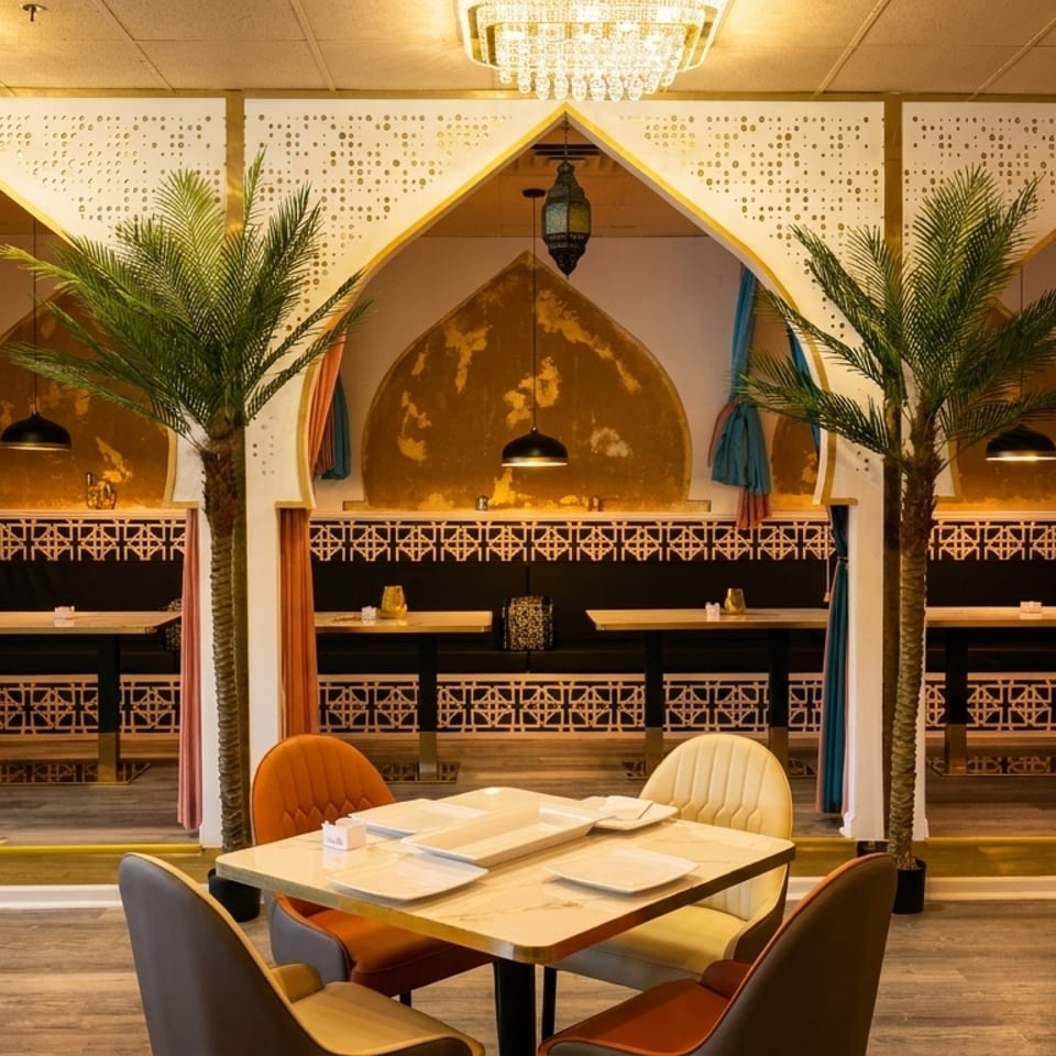 Restaurant interior with Moroccan-inspired decor, arched booths, palm trees, and modern dining tables.